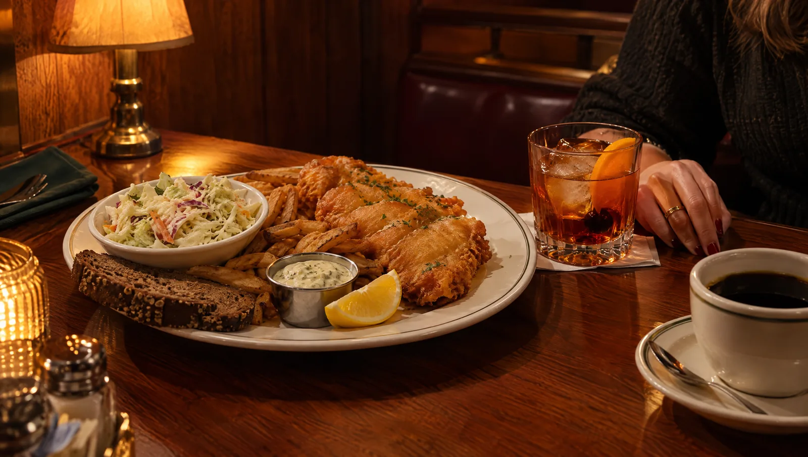 Wisconsin supper club table with a Friday fish fry, an old fashioned cocktail, and coffee under warm amber light